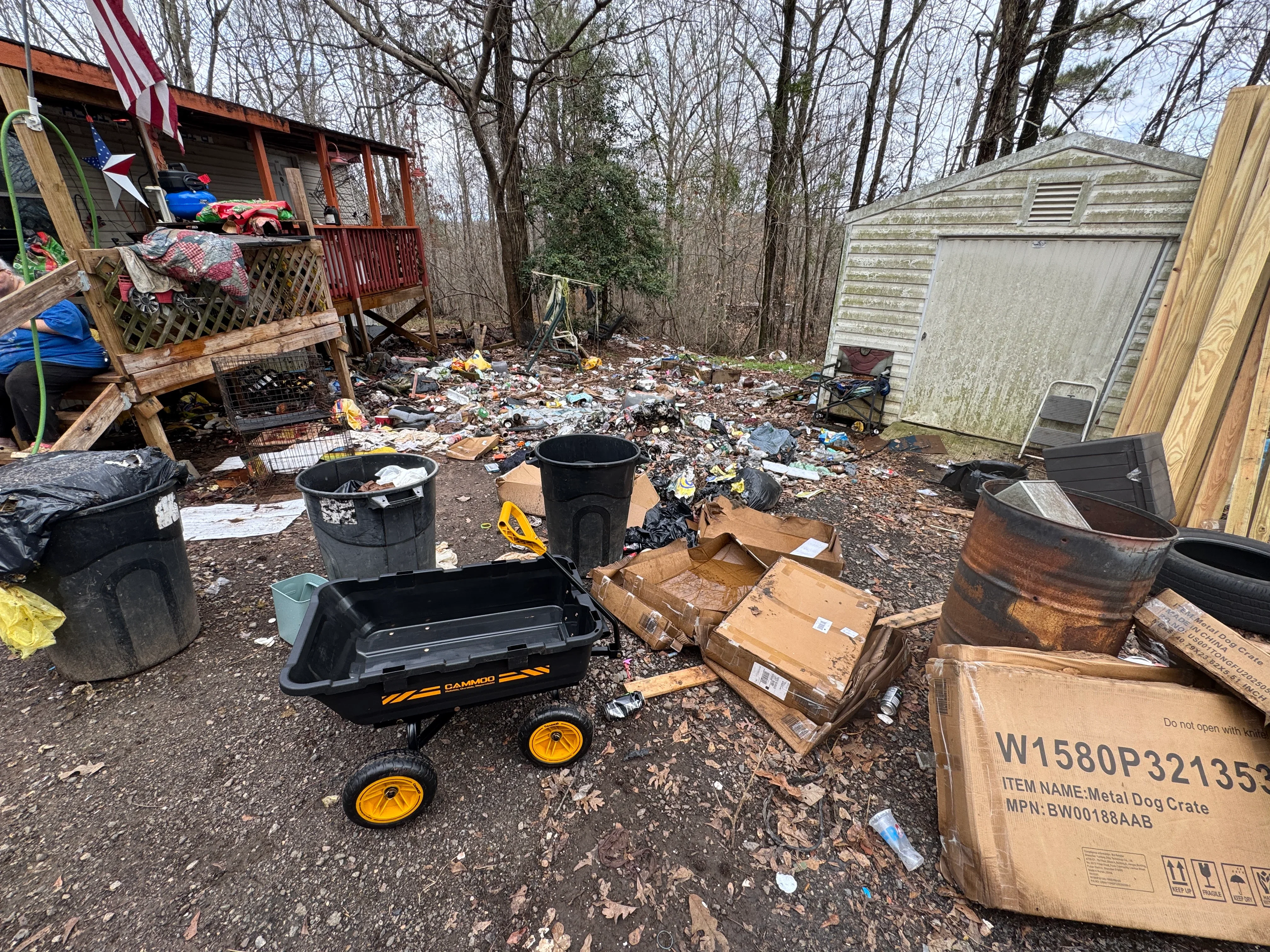 Junk removal project with debris, trash containers, cardboard boxes, and metal drums cleared from property