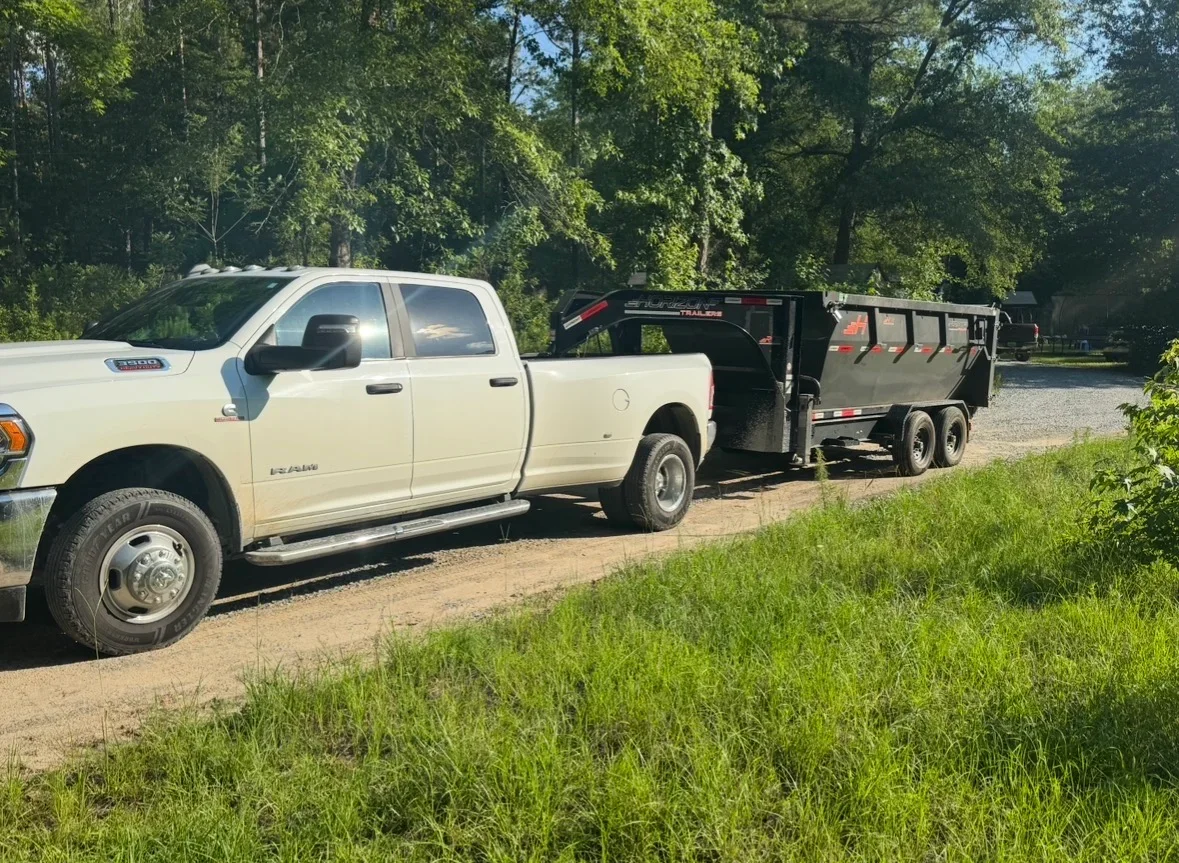 White pickup truck with tandem axle dump trailer for hauling and debris removal