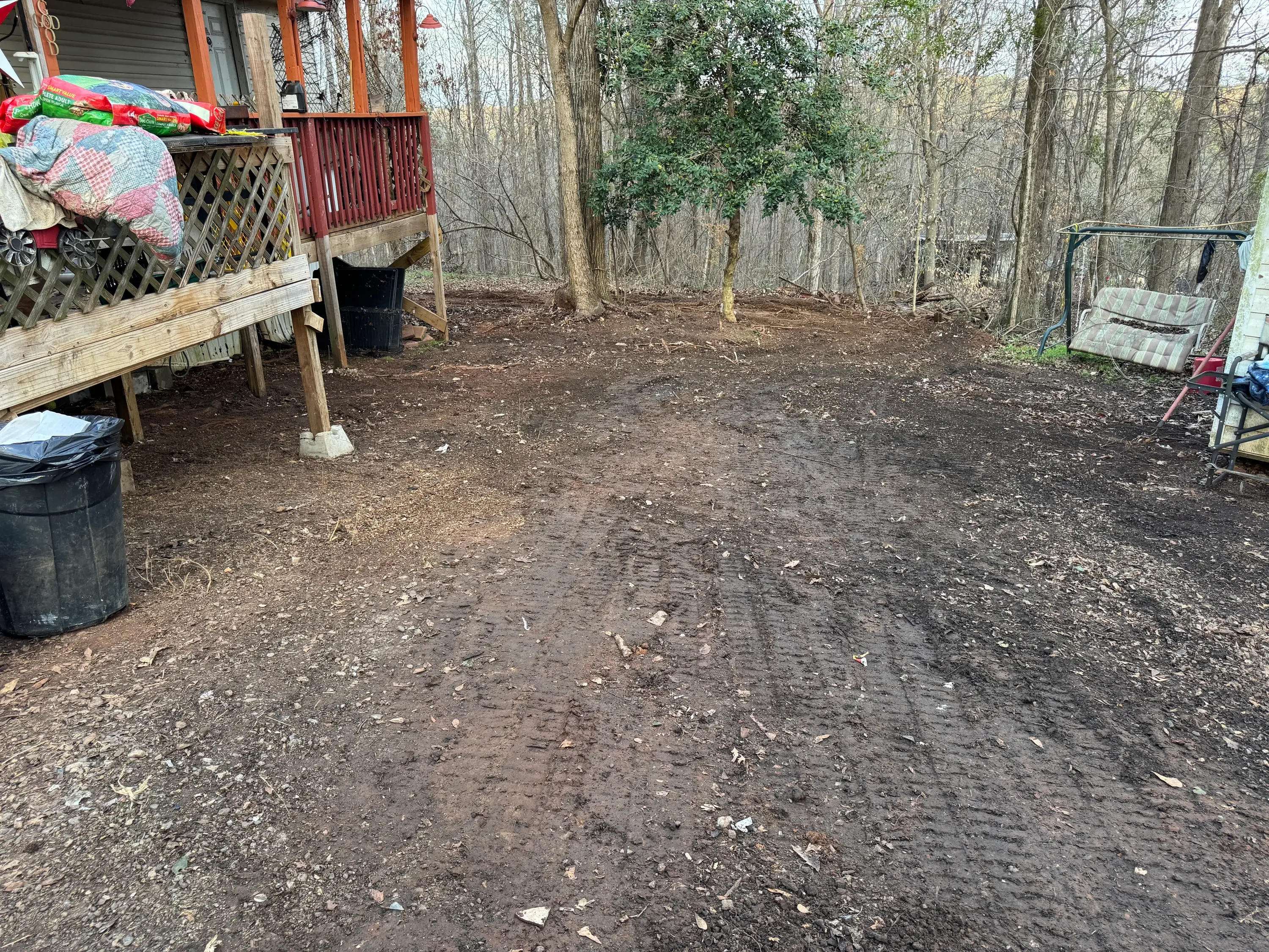 Cleared dirt backyard with removed debris and materials, wooded setting