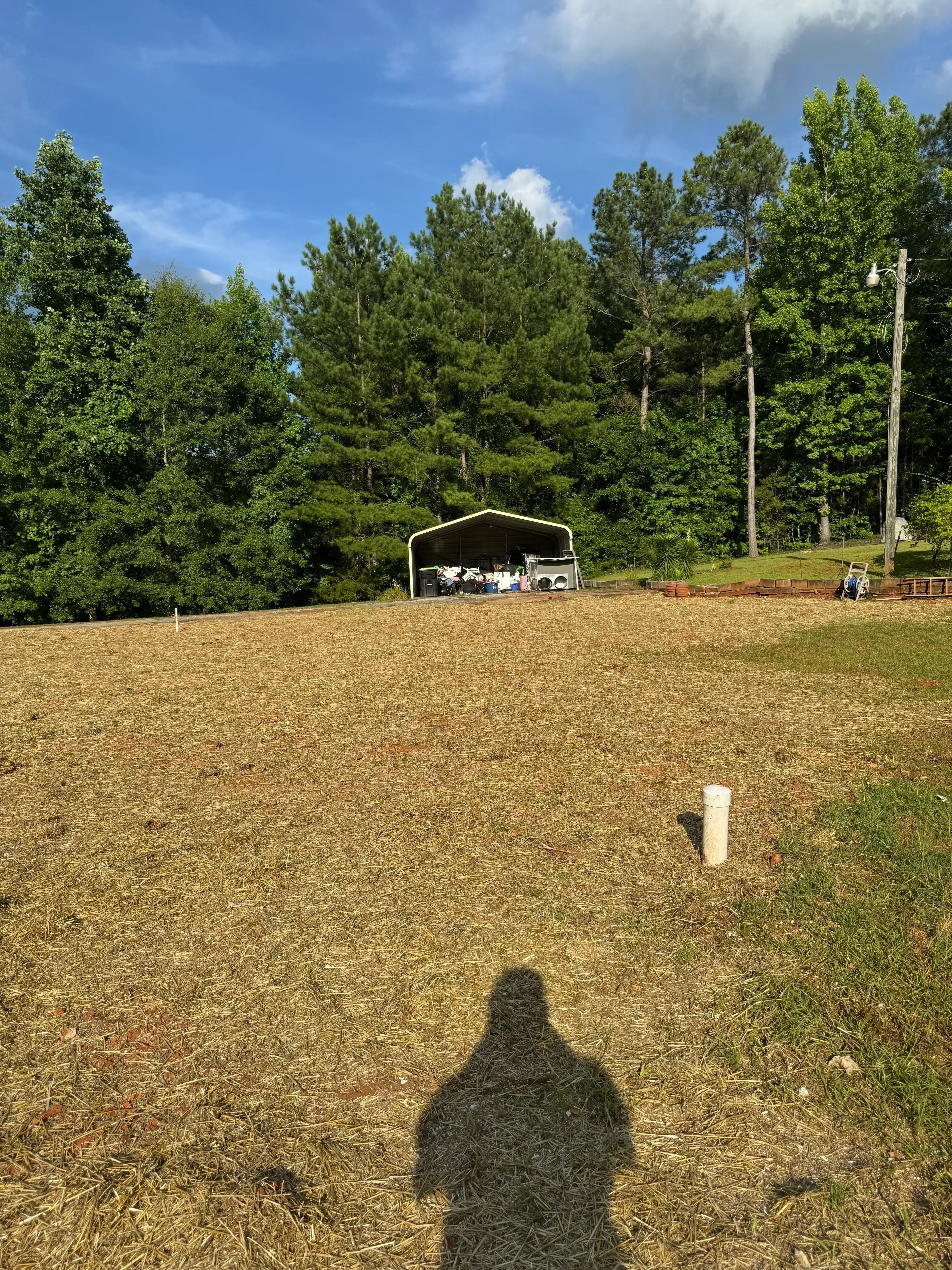 Cleared lot with removed vegetation, dirt surface, and metal fencing along property line
