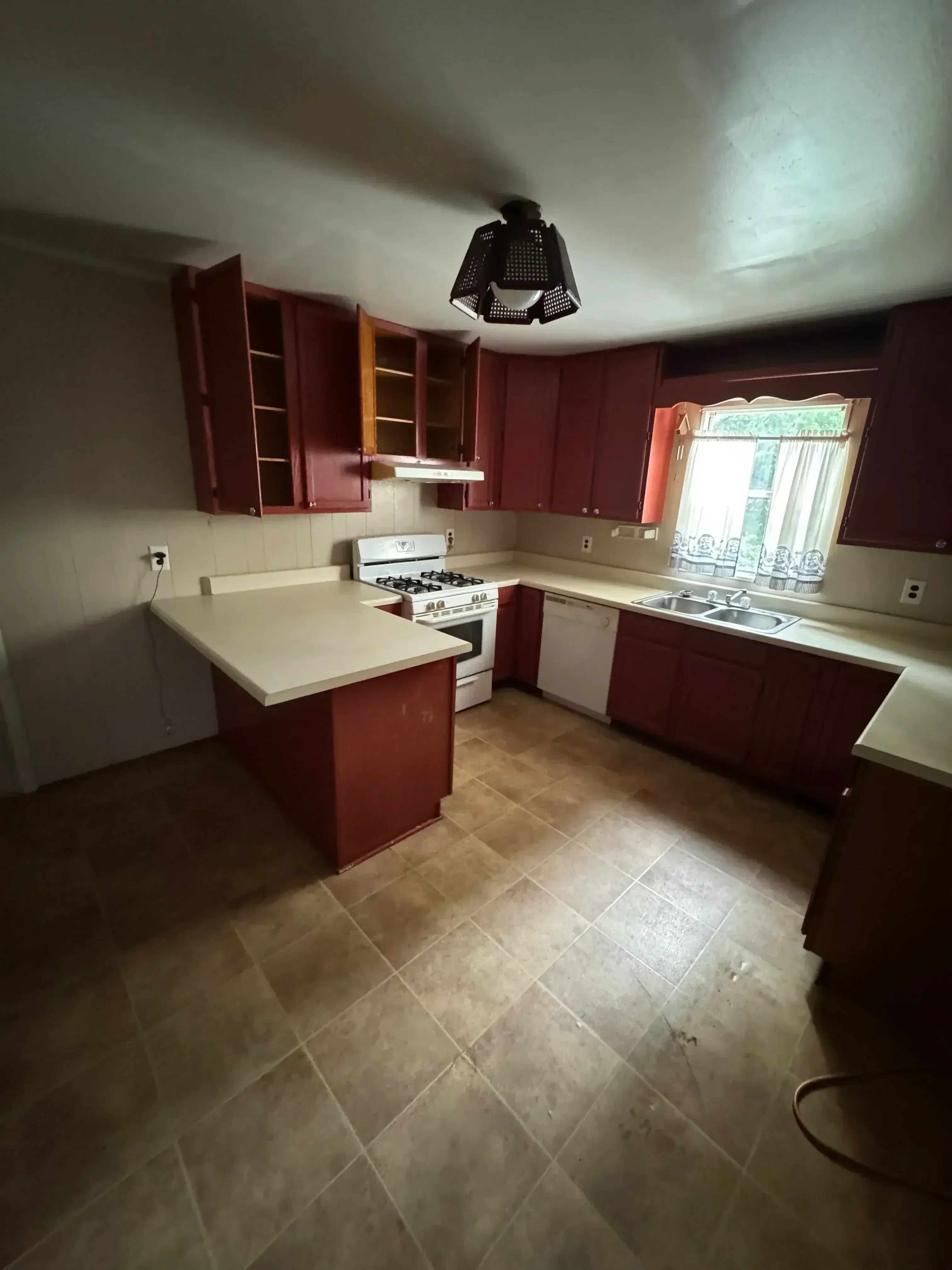 Kitchen demolition showing removed red cabinets, white appliances, and tile flooring