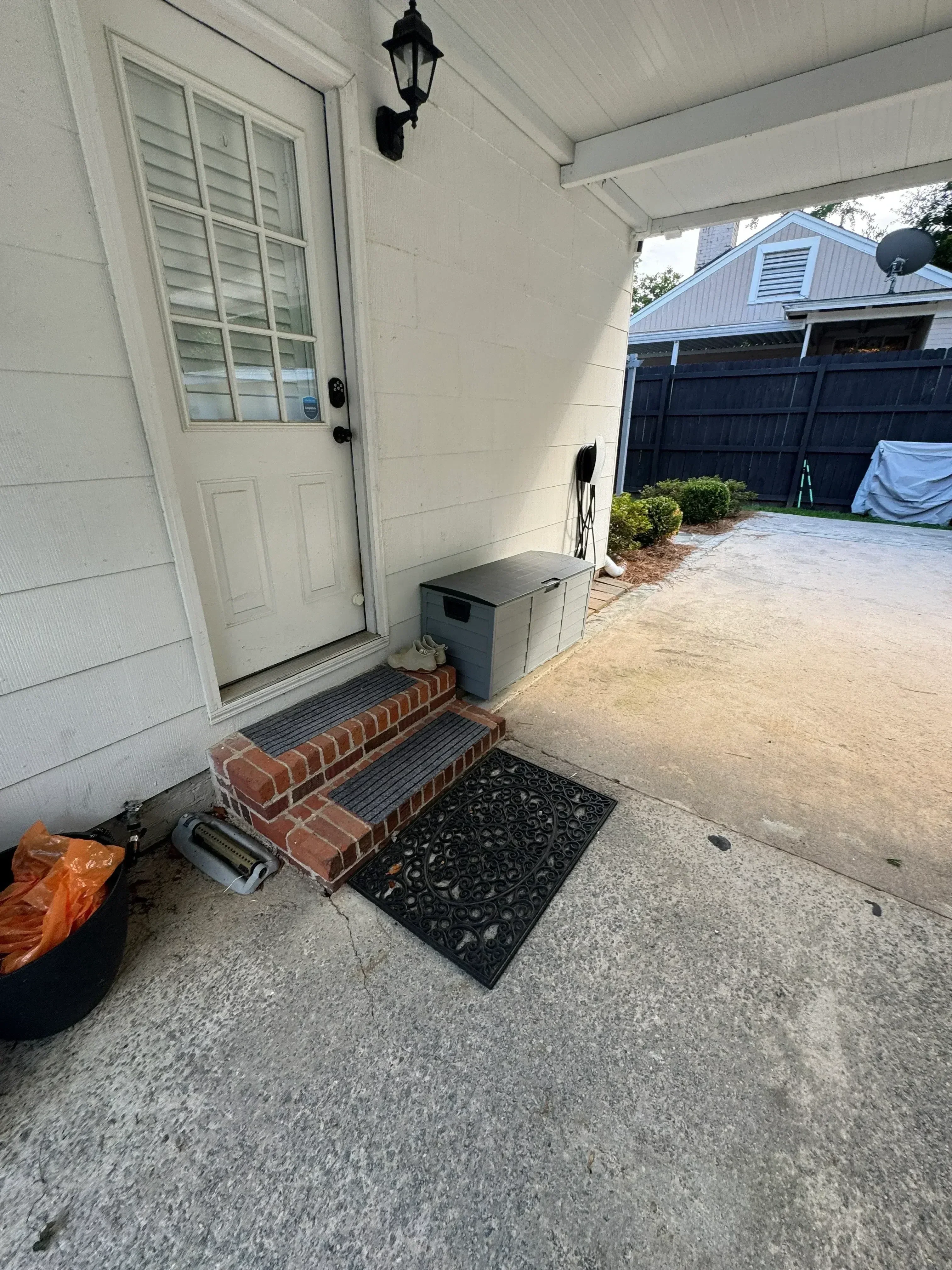 Residential entryway demolition showing removed metal gate, brick foundation, and concrete pad debris