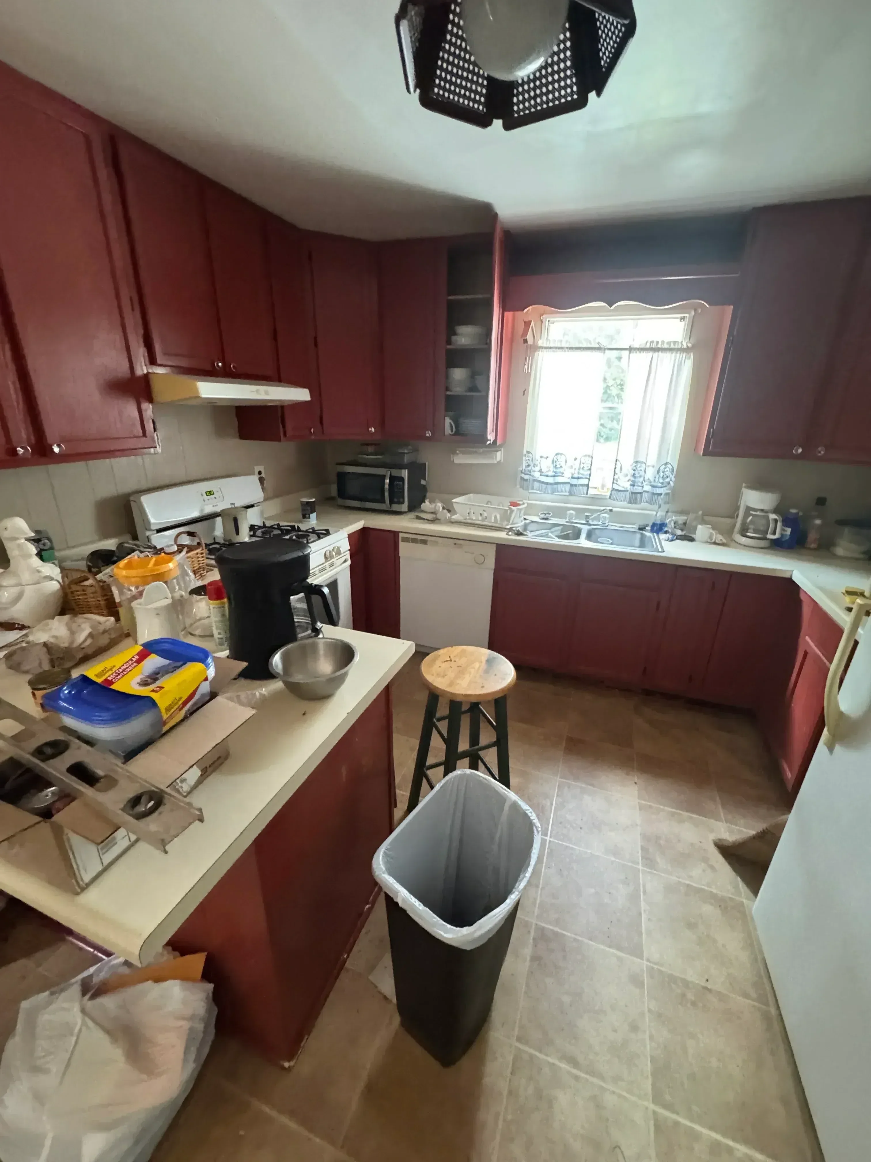 Kitchen demolition with red cabinetry removal, tile backsplash, and staged debris
