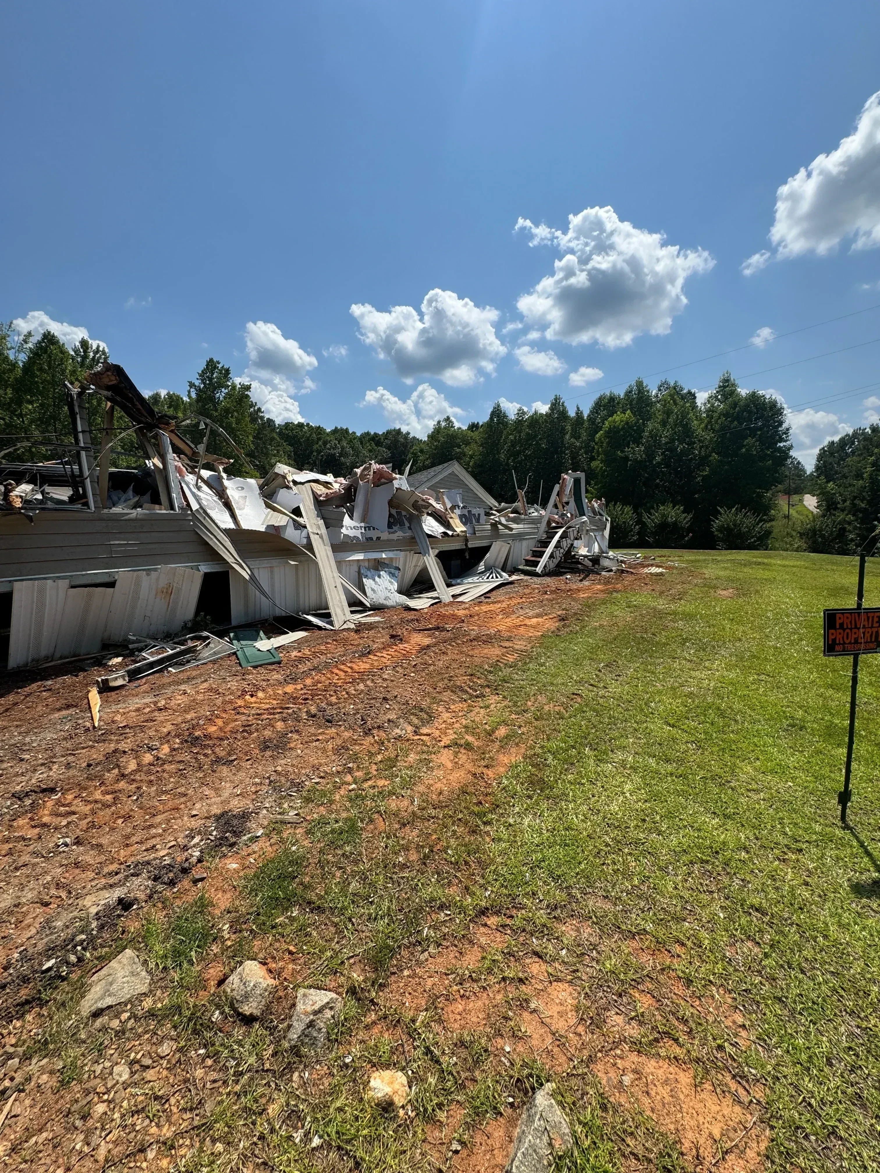 Demolished residential building with brick foundation and wood debris removal in progress